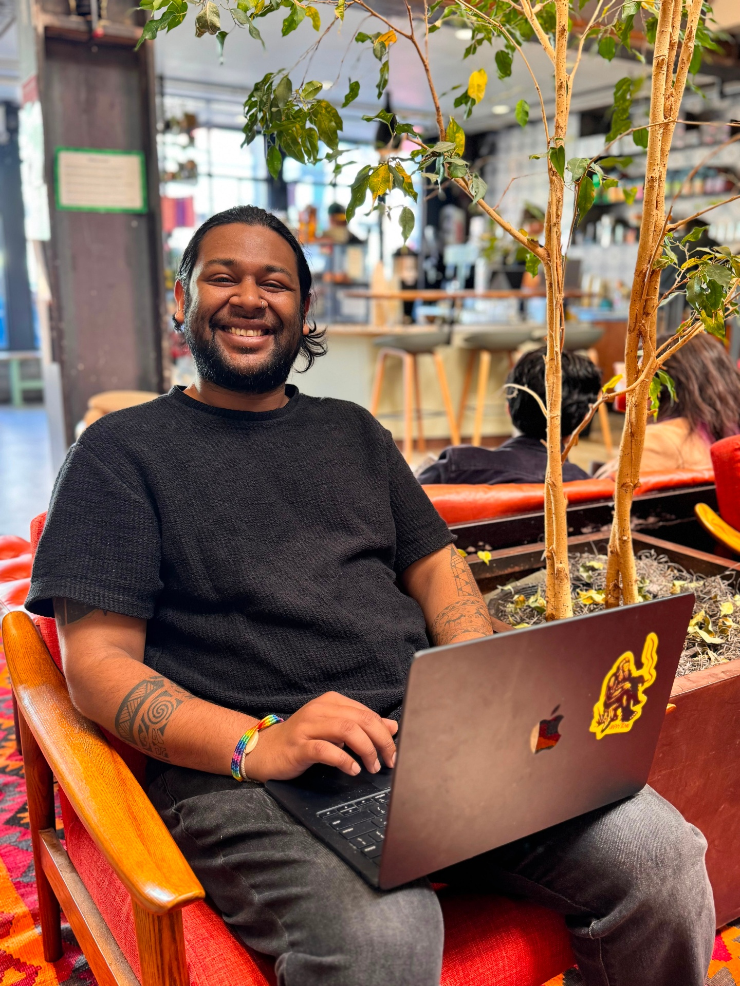 Moiz Arenpurwala smiling with his laptop at a San Francisco cafe